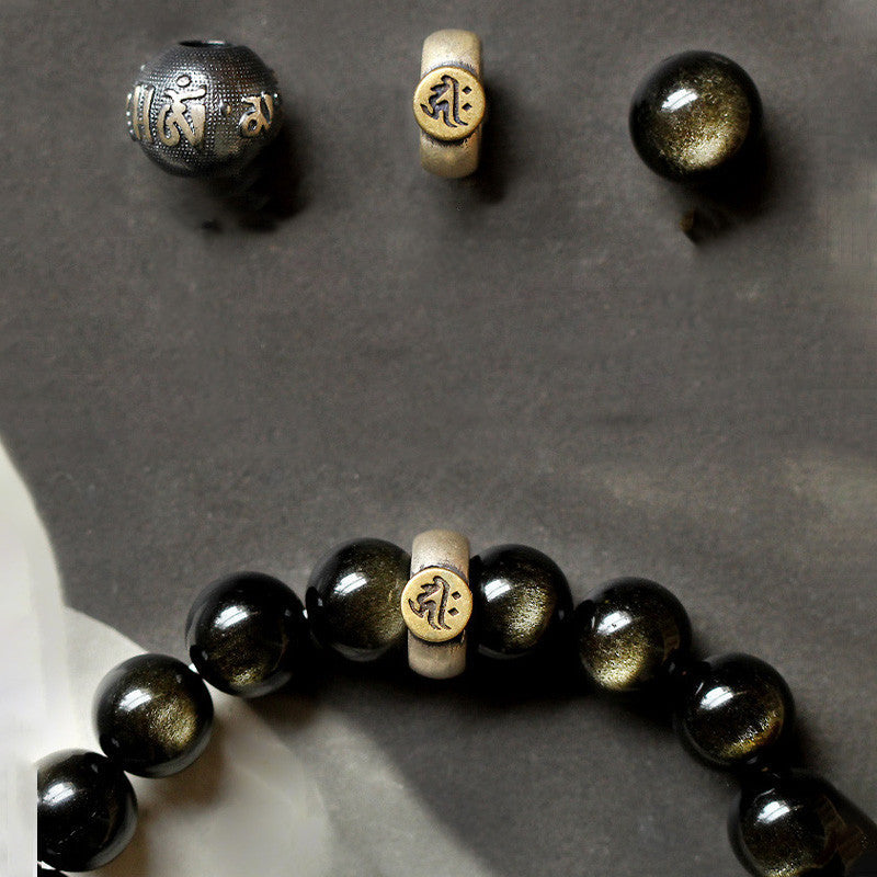 Zodiac Natal Buddha Obsidian Silver Bracelet - Flat lay with loose mantra beads on gray stone
