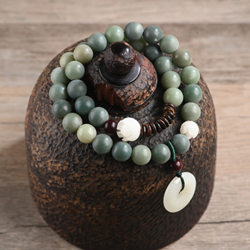 Cyan Bodhi Seed Jade Peace Buckle Bracelet - beads draped on rustic ceramic vessel, artisan display