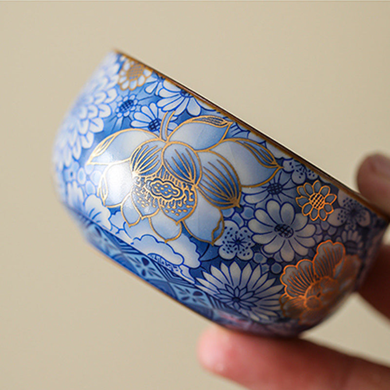 Lotus Chrysanthemum Ceramic Tea Cup - Blue-white floral cup in hand with gold lotus accent, refined