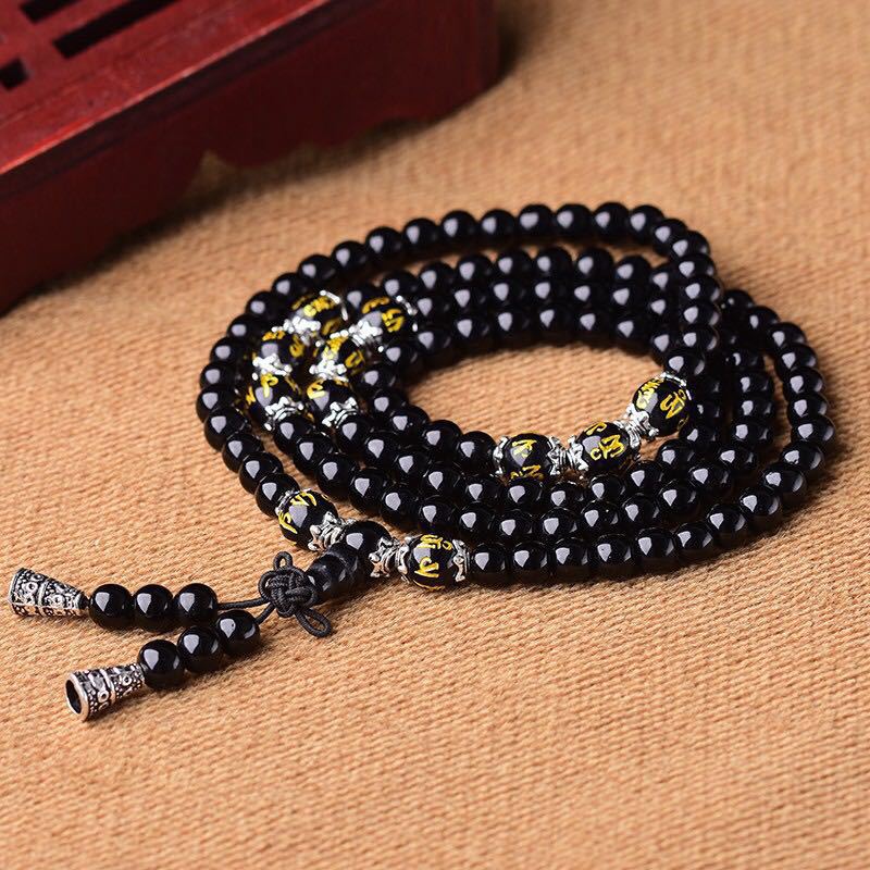 Black Obsidian Mala Bracelet - Loose coils on burlap fabric showing gold mantra beads and silver spacers, obsidian mala