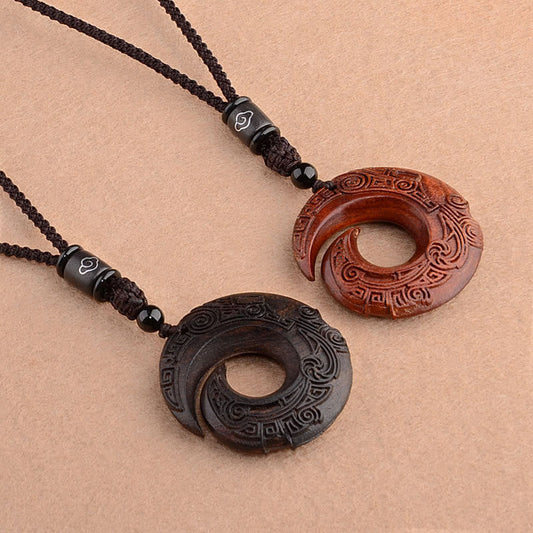 Red sandalwood ebony wood peace buckle pendant pair showing dark ebony and reddish-brown sandalwood spiral disc variants with carved geometric cloud patterns on braided cord