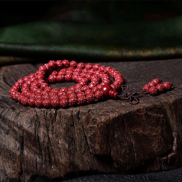 108 Mala Beads Cinnabar Bracelet – Low angle on wooden slab, carved red beads