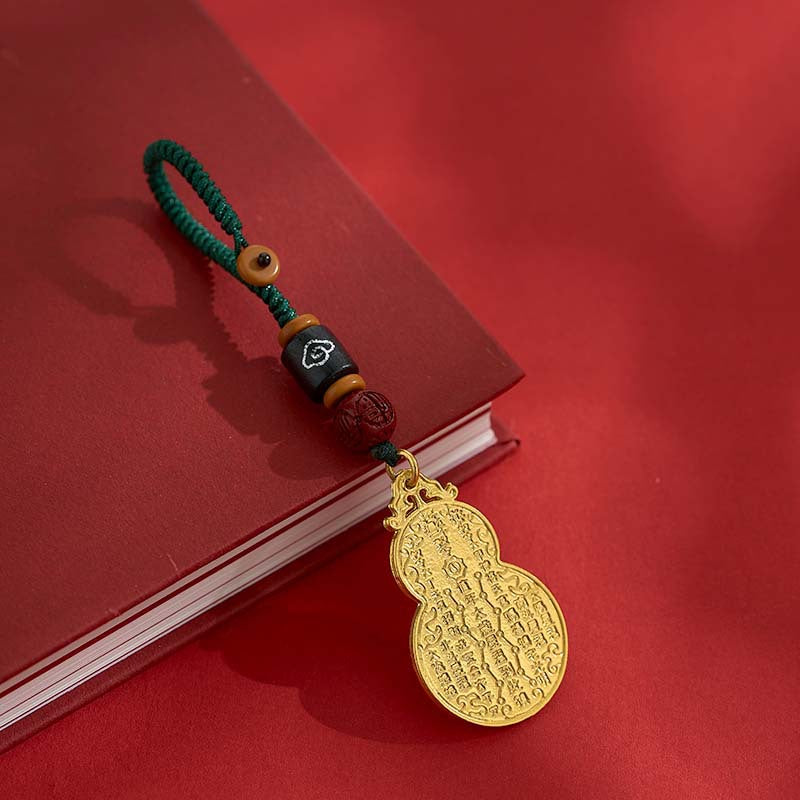 Antique gold gourd keychain with green cord and black bead on red book