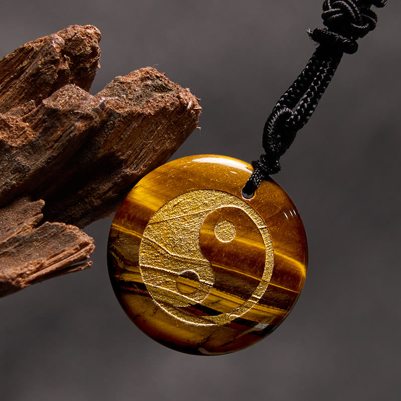 Yin Yang Crystal Necklace – Tiger eye stone round pendant with gold yin-yang engraving, golden-brown chatoyant banding on bla