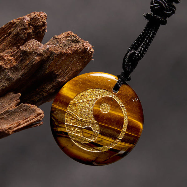 Yin Yang Crystal Necklace – Tiger eye stone round pendant with gold yin-yang engraving, golden-brown chatoyant banding on bla