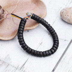 Coconut Shell Mantra Bracelet - Black prayer beads on dried botanical prop, distressed wood background