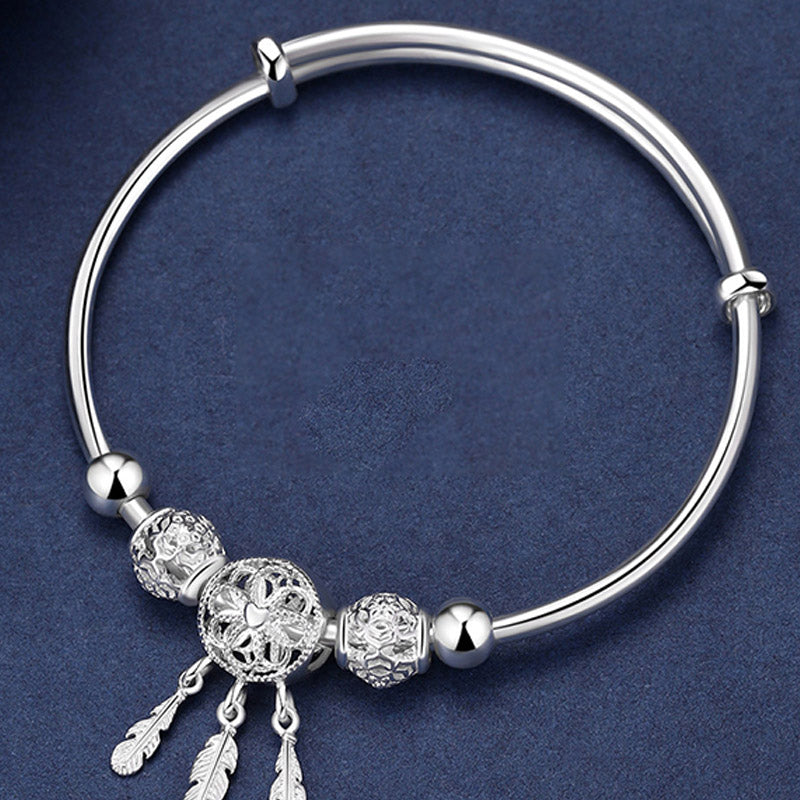 Dream Catcher Blessing Bracelet – Top-down flat lay of silver bangle with dreamcatcher charms, overhead view