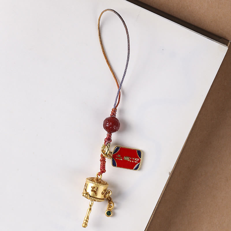 Prayer Wheel Phone Charm – Flat lay on white and kraft paper, Om Mani Padme Hum