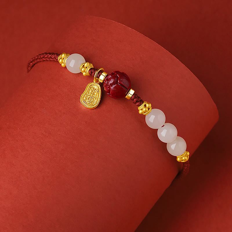 24K Gold Jade Cinnabar Lotus Bracelet – Red cord bracelet with gold lotus accents, white jade and carved cinnabar lotus bead on curved red surface
