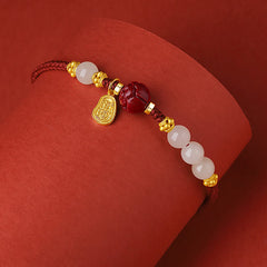 24K Gold Jade Cinnabar Lotus Bracelet – Red cord bracelet with gold lotus accents, white jade and carved cinnabar lotus bead on curved red surface