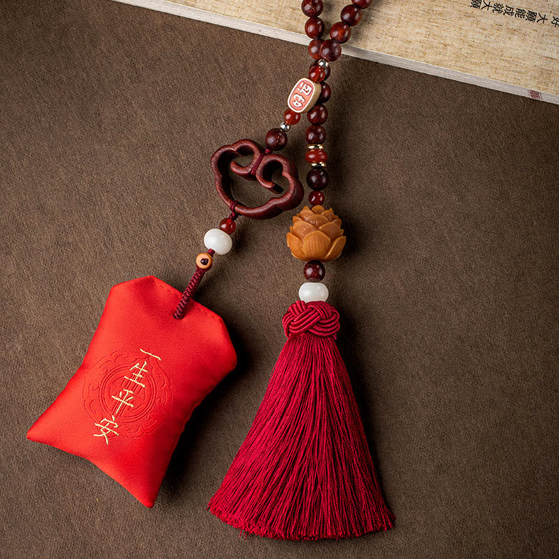 Red Sandalwood Car Hanging – Close detail of carved lotus flower bead with red wooden beads on neutral brown background