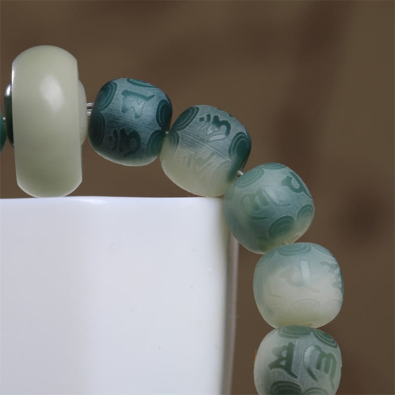 Bodhi Seed Om Mani Padme Hum Bracelet – Macro detail of Sanskrit carved beads with gradient green coloring, mala bracelet