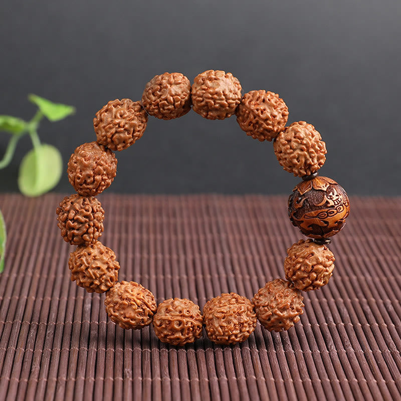 Rudraksha PiXiu Bracelet – On brown woven mat with green leaf accent, warm tone spiritual jewelry