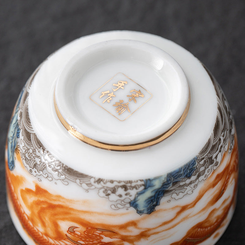 Dragon Phoenix Crane Gilt Ceramic Teacup – filled with amber tea showing gold interior, hand-painted dragon on cream exterior, elegant