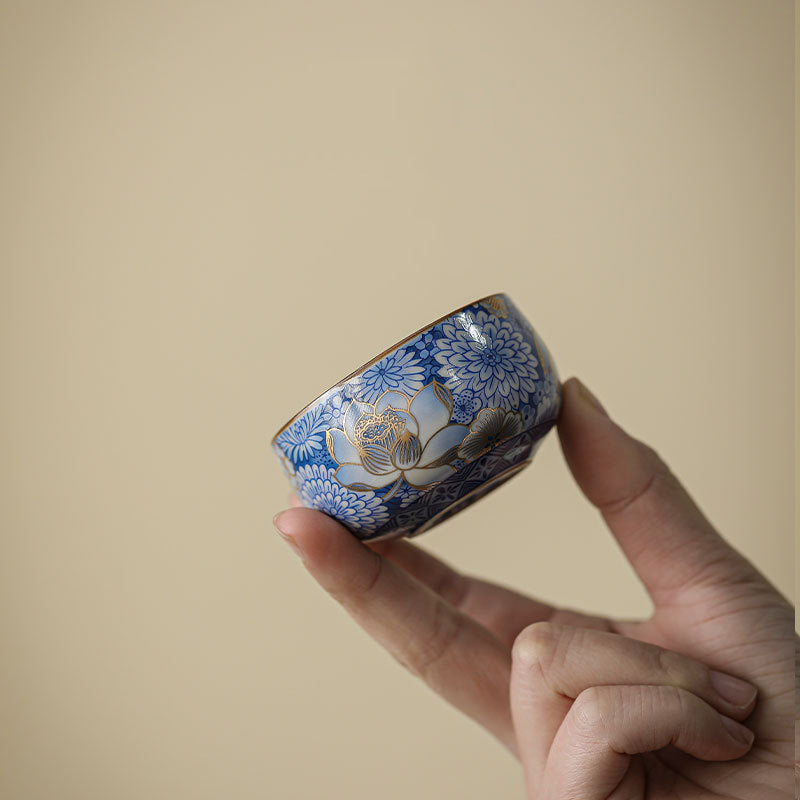 Lotus Chrysanthemum Ceramic Tea Cup - Tilted view revealing gold lotus on blue-white porcelain, luxury