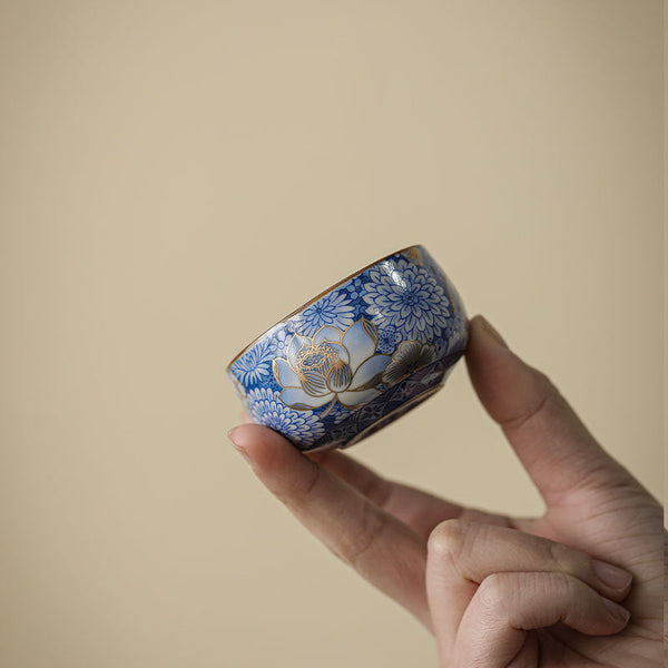 Lotus Chrysanthemum Ceramic Tea Cup - Tilted view revealing gold lotus on blue-white porcelain, luxury