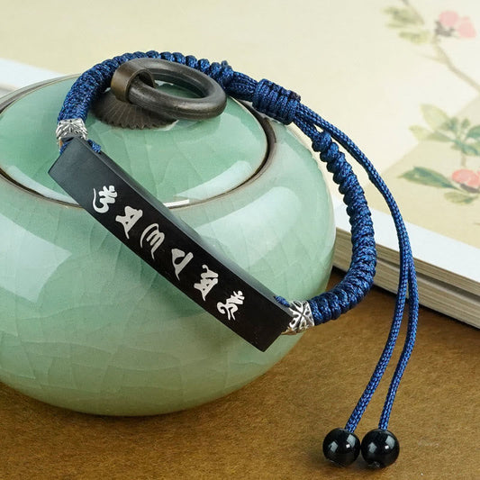 Ebony Wood Mantra Bracelet – Side view on celadon ceramic vessel, silver inlaid Sanskrit engraving