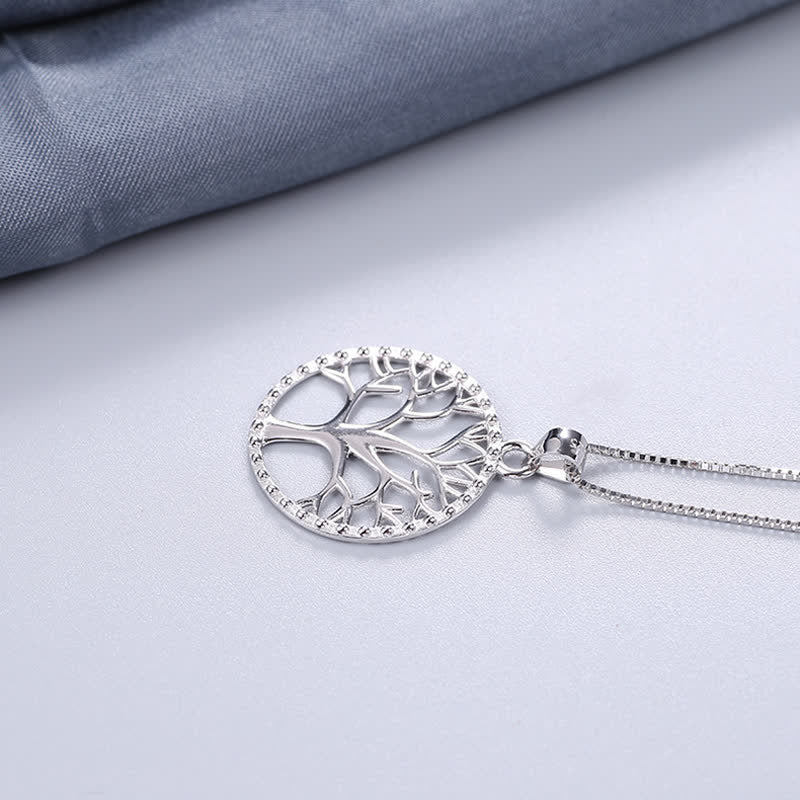 Tree of Life Sterling Silver Necklace – pendant on matte white with blue fabric corner, chain trailing, sterling silver
