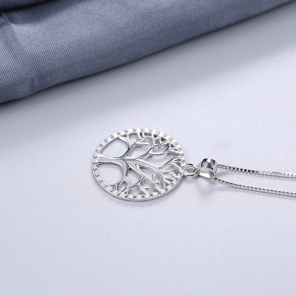 Tree of Life Sterling Silver Necklace – pendant on matte white with blue fabric corner, chain trailing, sterling silver
