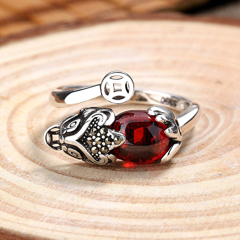 Feng Shui Garnet Pixiu Ring – front view on wood slice, red garnet center with silver pixiu wealth protection ring