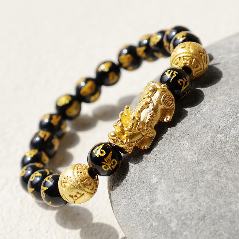 FengShui PiXiu Obsidian Wealth Bracelet - Macro shot on gray stone, Pixiu charm detail with gold mantra beads, feng shui jewelry