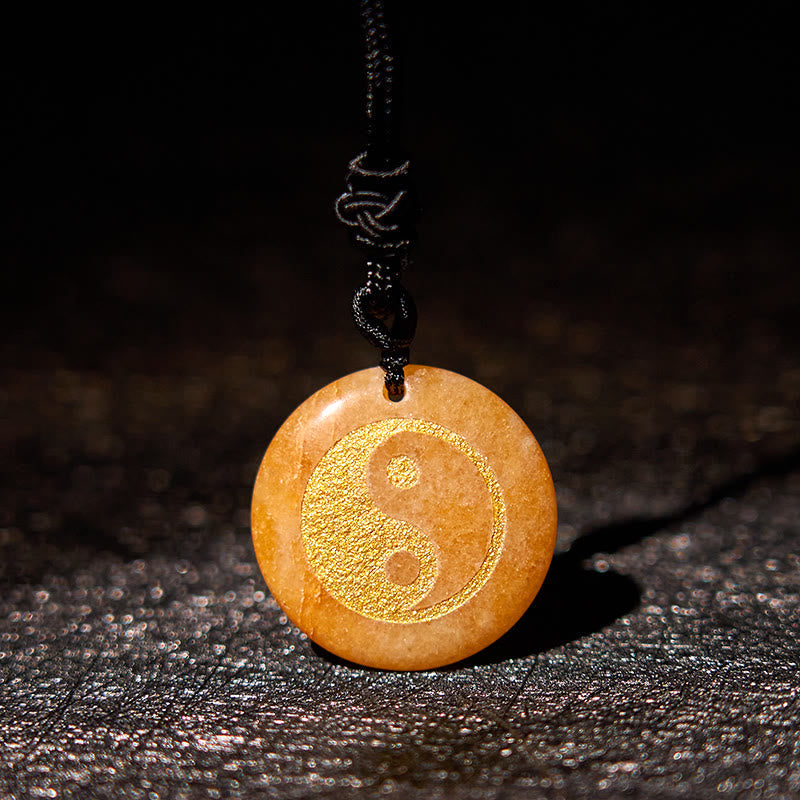 Yin Yang Crystal Necklace – Circular orange aventurine pendant with gold yin-yang engraving, marbled semi-precious stone on b