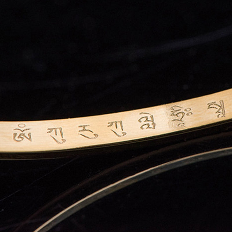 Om Mani Padme Hum Engraved Bracelet – gold band macro showing Tibetan mantra engraving, detail shot