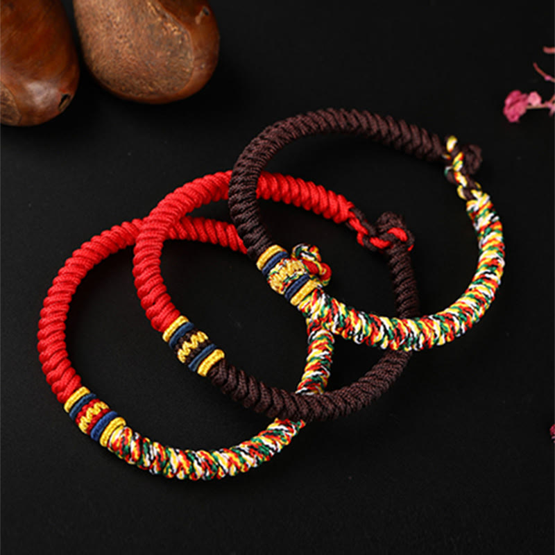 Three handmade Tibetan five-color king kong knot bracelets in red and brown stacked together showing multicolor braided patterns with gold accent bands