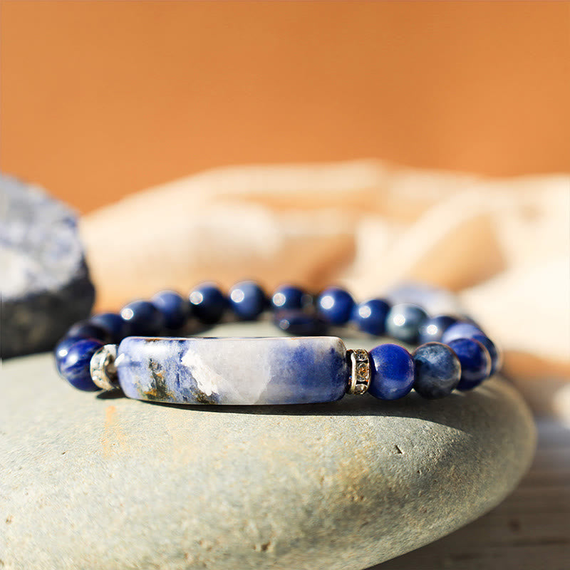 Natural Multi-Stone Love Heart Healing Bracelet - Blue sodalite bracelet on gray stone surface with marbled bar centerpiece and natural mineral patterning