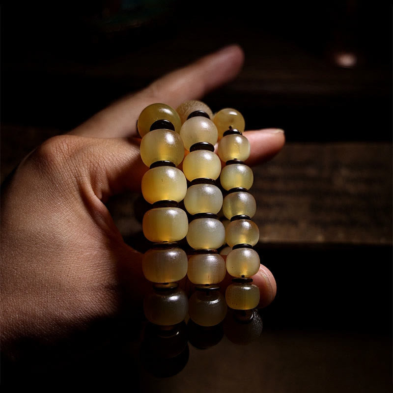 Tibetan Sheep Horn Skull Bracelet – Three bracelets held in hand on reflective dark surface, warm amber glow