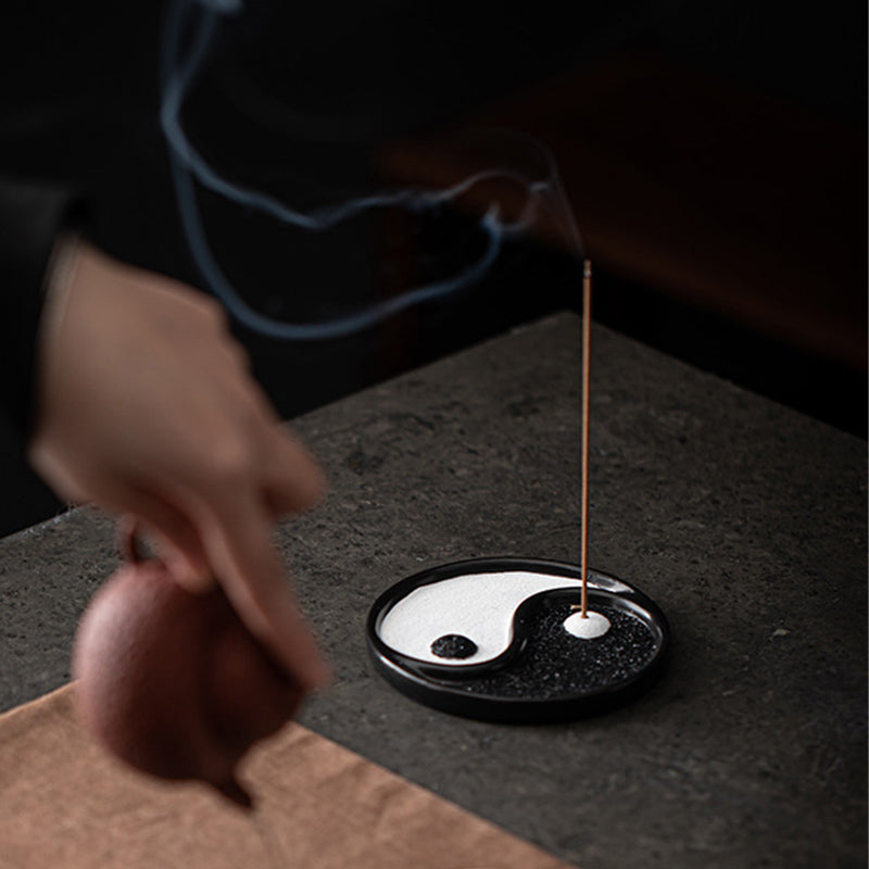 Yin Yang Incense Holder – Smoke from yin-yang dish beside blurred teapot hand, Atmospheric