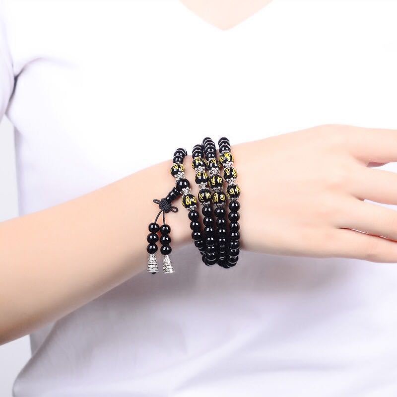 Black Obsidian Mala Bracelet - Worn on wrist against white background with gold mantra beads, obsidian prayer bracelet