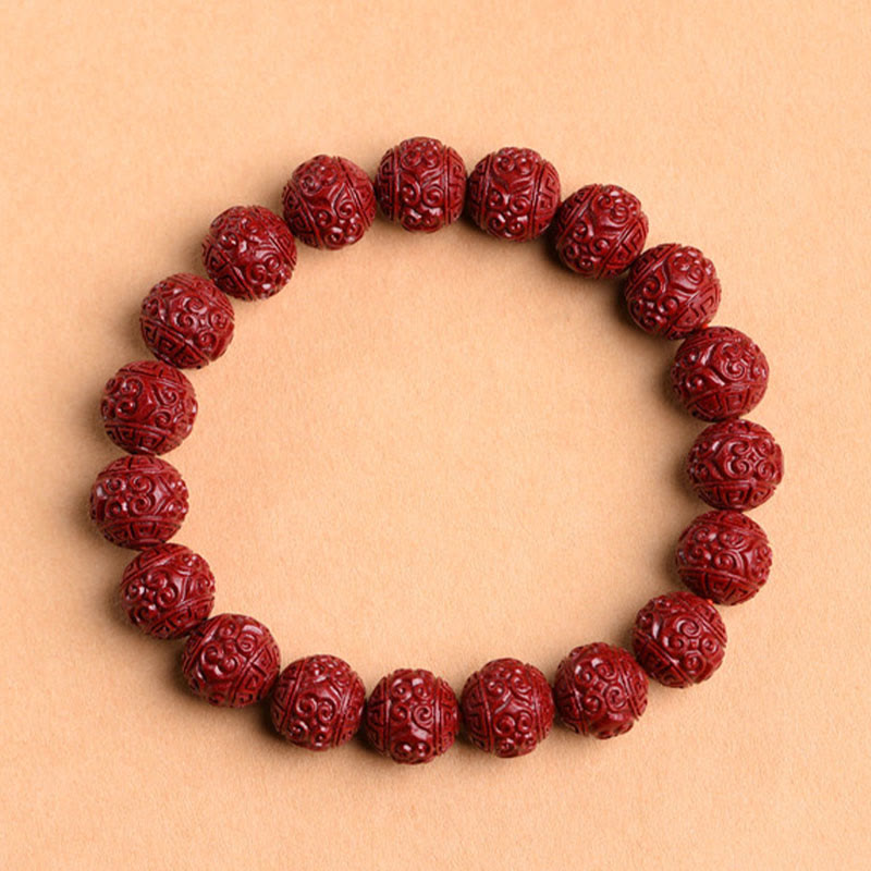 Cinnabar Om Mani Padme Hum Bracelet – scrollwork carved crimson beads flat lay, beaded cinnabar jewelry