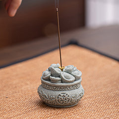 Fu Character Sandstone Incense Burner – smoke rising from lit incense on orange mat, sandstone burner