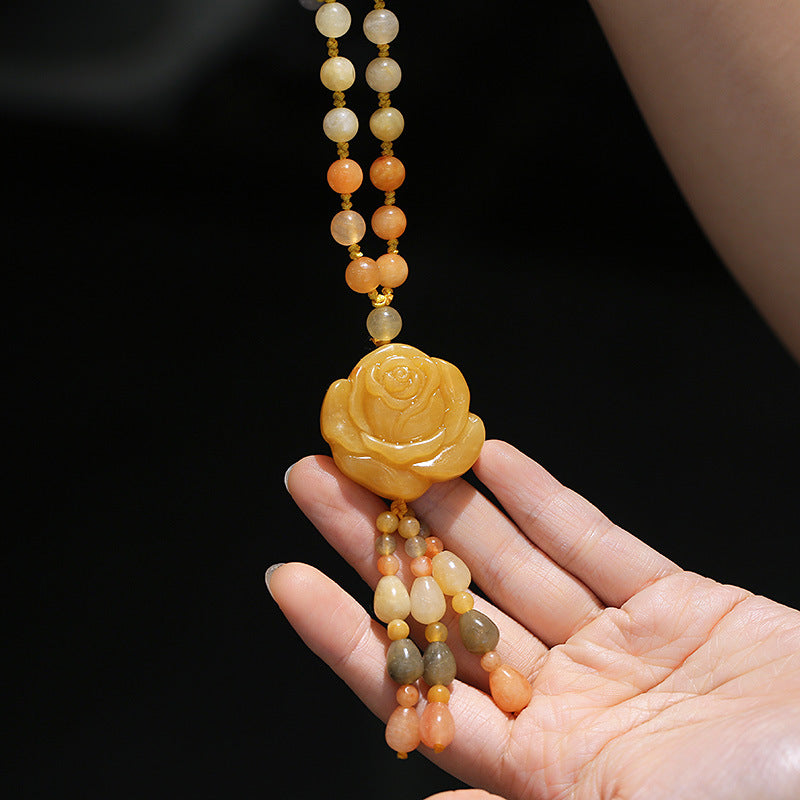 Golden Silk Jade Flower Pendant Necklace – dual strand beads with carved rose pendant and tassel drops, palm-up hand display