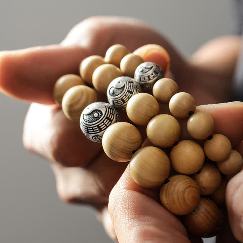 Peach Wood Cinnabar Bracelet – Three bagua yin yang beads in hand close-up, Taoist protection