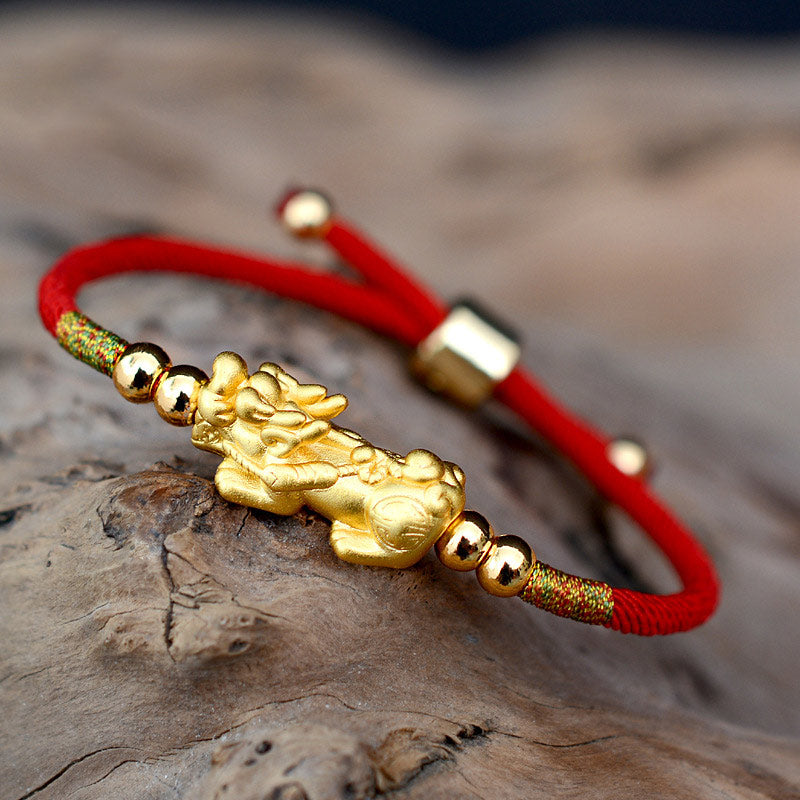 Gold-Plated PiXiu Red String Bracelet – gold PiXiu on adjustable red cord with gold beads, stone background Hauptbild