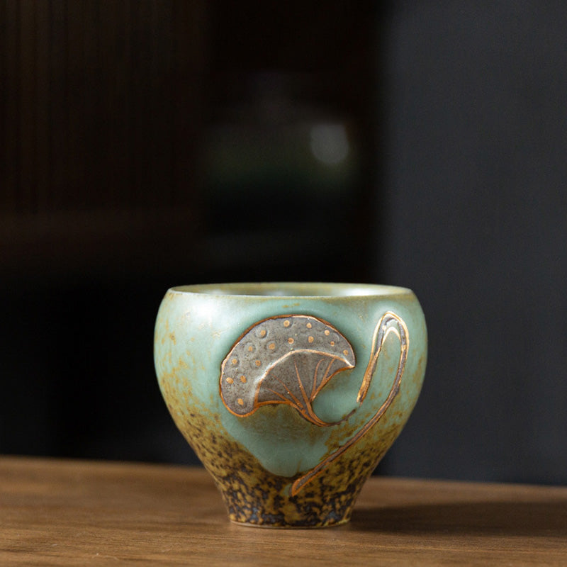 Lotus Pod Ceramic Kung Fu Tea Cup - Celadon green glaze with bronze ginkgo leaf relief on dark wood, artisanal