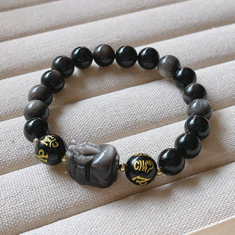 Om Mani Padme Hum Bracelet – Silver sheen obsidian beads with PiXiu on cream fabric display, meditation bracelet