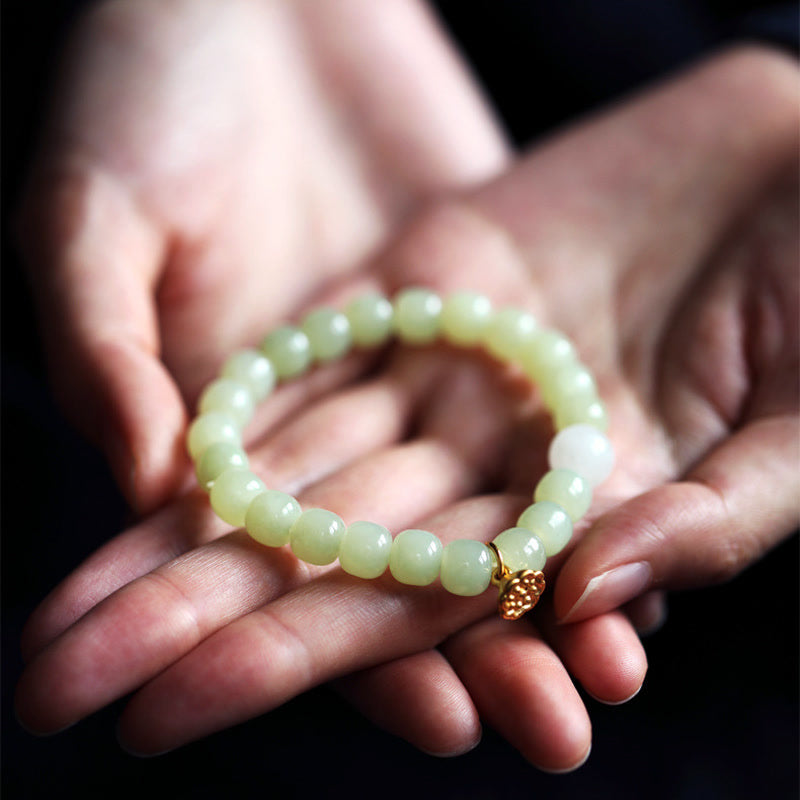 Jade Lotus Abundance Bracelet – Celadon beads with gold lotus pod charm cradled in hands, nephrite jade bracelet