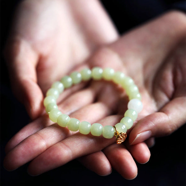 Jade Lotus Abundance Bracelet – Celadon beads with gold lotus pod charm cradled in hands, nephrite jade bracelet