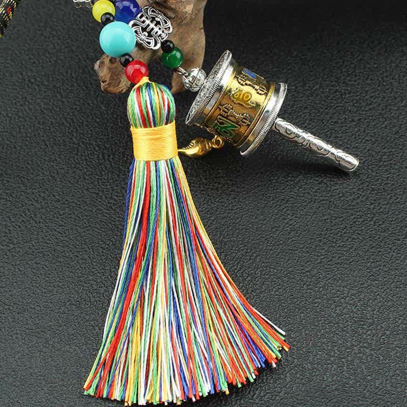 Tibetan Prayer Wheel Tassel – Close-up brass prayer wheel with colored mantras and rainbow tassel