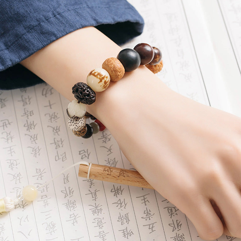 Bodhi Seed Lotus Mala – On wrist resting on calligraphy scroll with bamboo, mindfulness bracelet