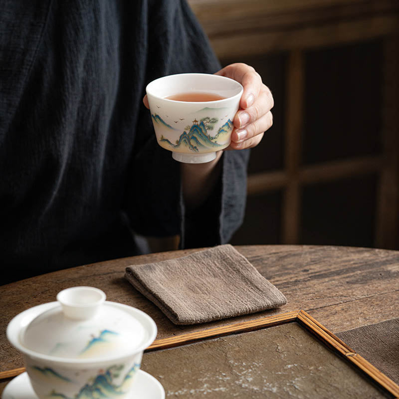 Ceramic Kung Fu Tea Cup – gold-outlined mountain peaks with orange pavilion on white background, blue-green tones
