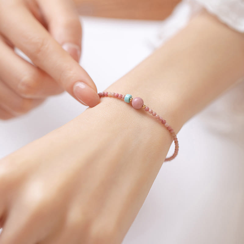 Rhodonite Loving Energy Bracelet – Pink stone beads with larger pink focal and turquoise bead worn with white eyelet lace cuff, elevated side angle