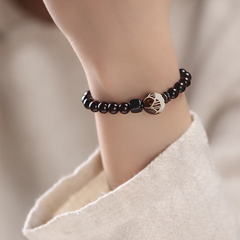 Red Sandalwood Lotus Bodhi Seed Bracelet – Dark wood mala bracelet worn on wrist with cream fabric, carved lotus detail