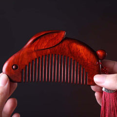 Close-up of hands holding red sandalwood bunny comb showing smooth wood grain