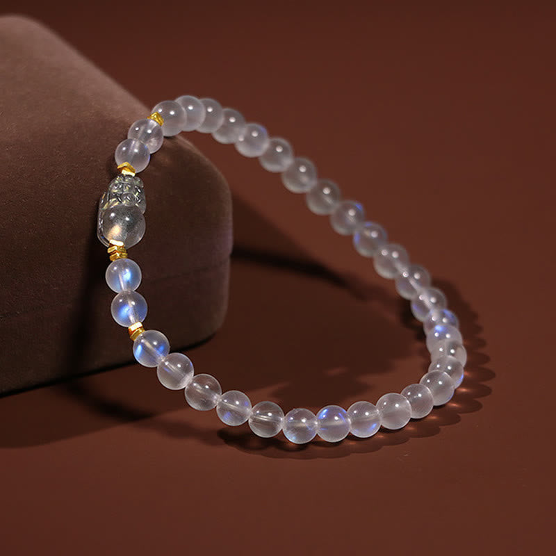 Moonstone PiXiu Bracelet – Moonstone beads draped over velvet cushion at angle, calming crystal bracelet