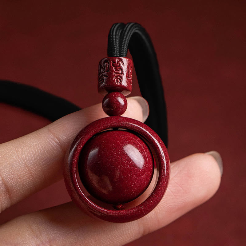 Cinnabar PiXiu Necklace – Hand holding black cord pendant close-up red bead detail, protection necklace