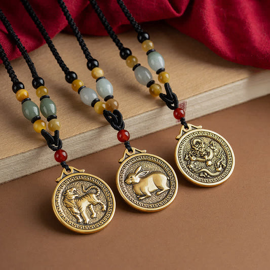 12 Chinese Zodiac Fortune Necklace Pendant – Three Chinese zodiac pendants featuring Tiger Rabbit and Dragon medallions in antique gold with jade and carnelian beaded cords, arranged diagonally on burgundy silk drape, zodiac collectible necklace set